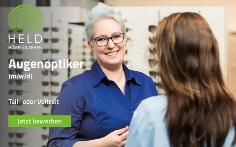 Stellenanzeige: Augenoptiker (m/w/d) in Teil- oder Vollzeit, eine Mitarbeiterin berät eine Kundin vor der Brillenwand