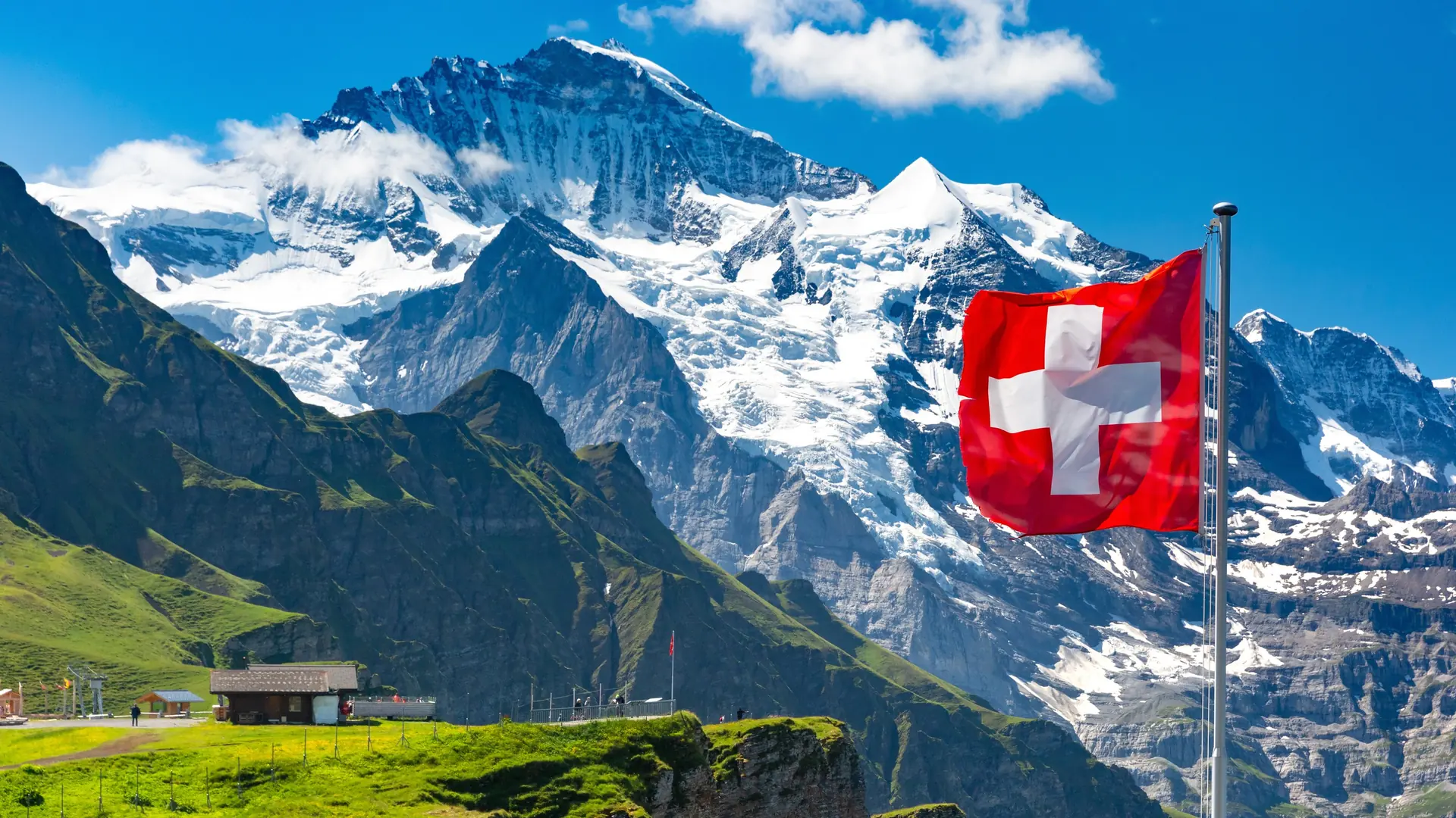 Schweizer Fahne vor verschneiten Berggipfeln